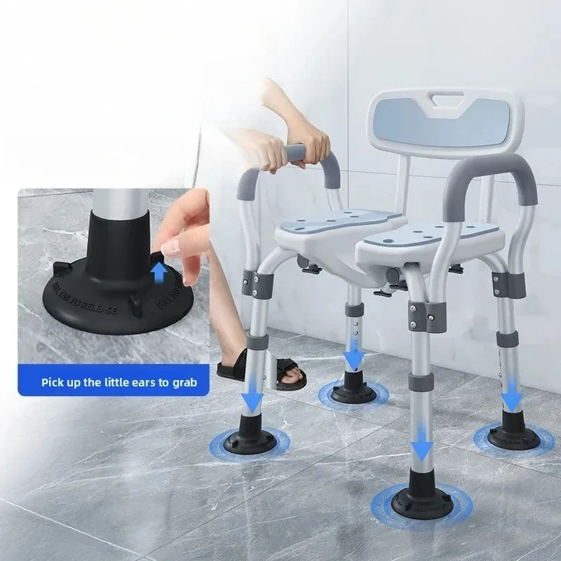 A silver and light blue bathroom height-adjustable safety chair with armrests and suction cup feet, shown in a bathroom setting with a person's legs and hands visible. An inset callout highlights the suction base and instructions say 'Pick up the little ears to grab'.